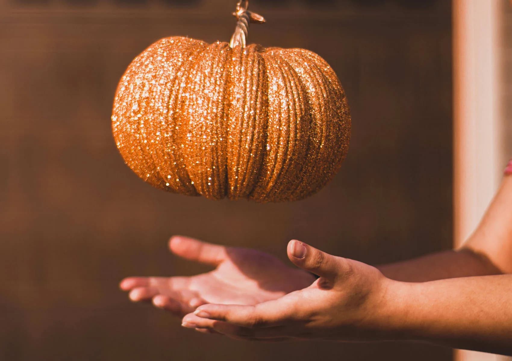 A pumpkin suspended above an outstretched hand.
